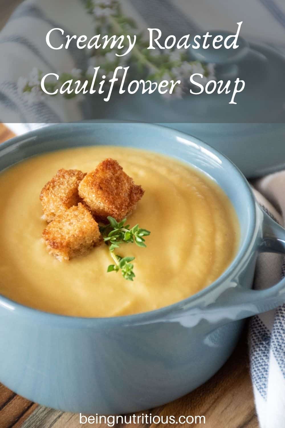 Small bowl of soup with croutons and fresh thyme. Text overlay: Creamy Roasted Cauliflower Soup.