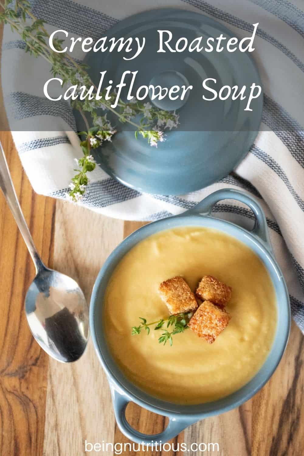Small bowl of soup with croutons and fresh thyme. Text overlay: Creamy Roasted Cauliflower Soup.