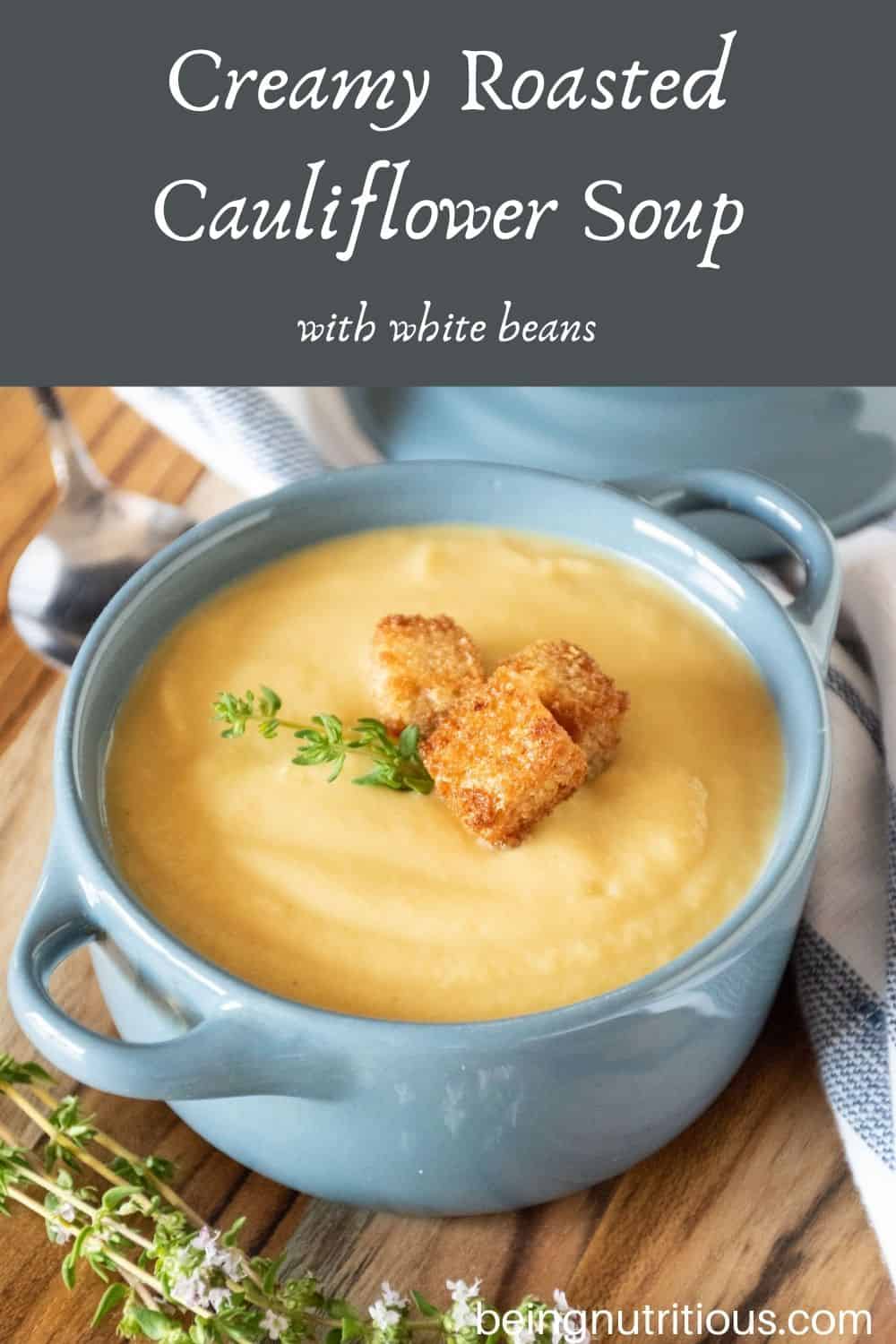 Small bowl of soup with croutons and fresh thyme. Text overlay: Creamy Roasted Cauliflower Soup; with white beans.
