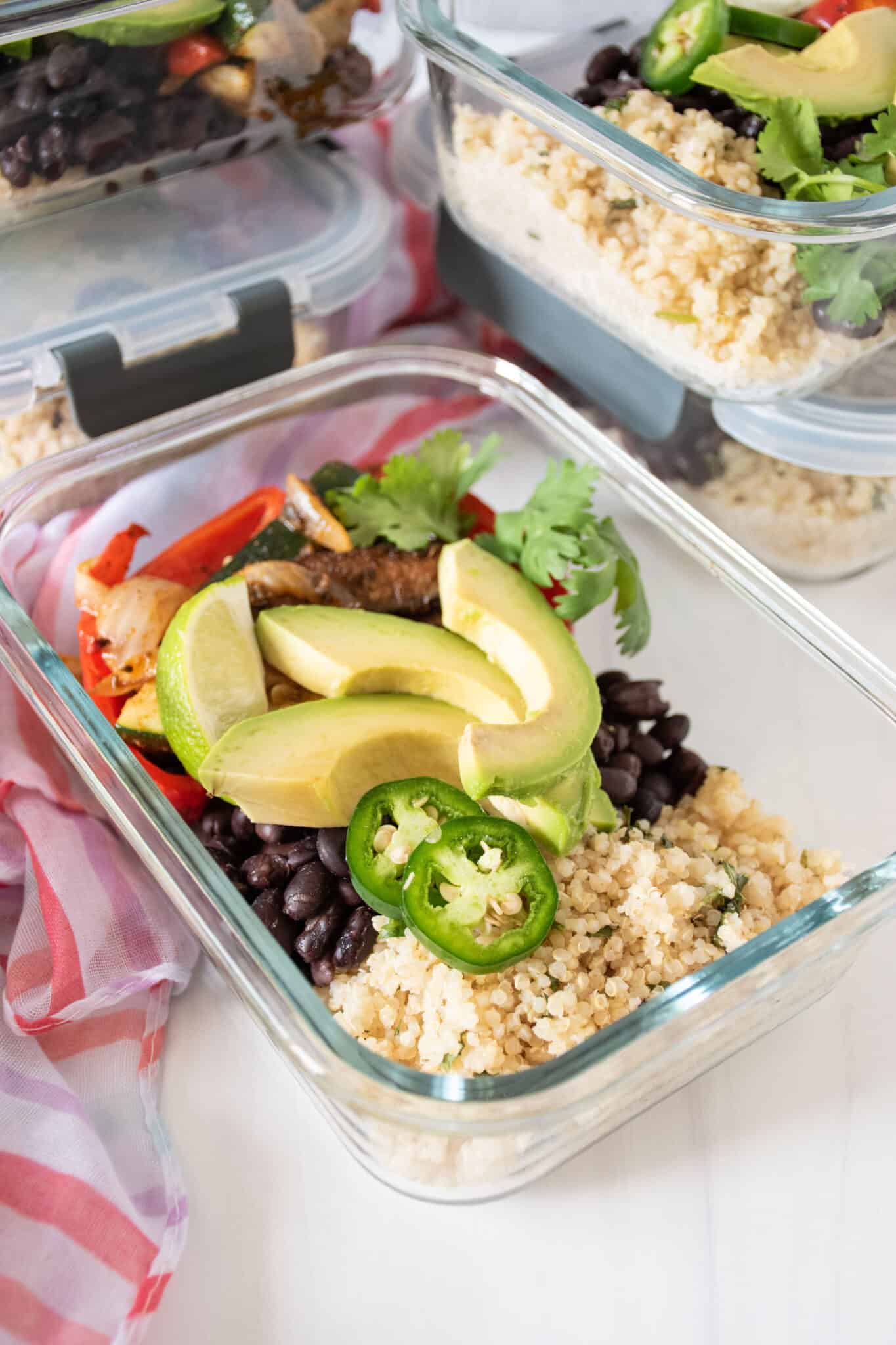 Glass meal prep container filled with burrito fillings. 4 more containers in the background.