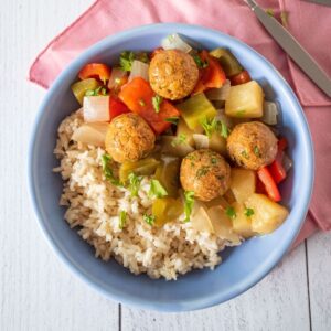 Bowl with rice, meatballs, and onions and bell peppers.