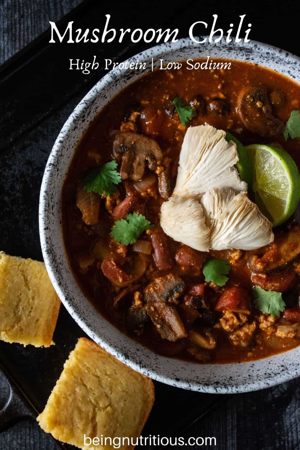Bowl of chili with squares of cornbread surrounding. Text overlay: Mushroom Chili; high protein, low sodium.