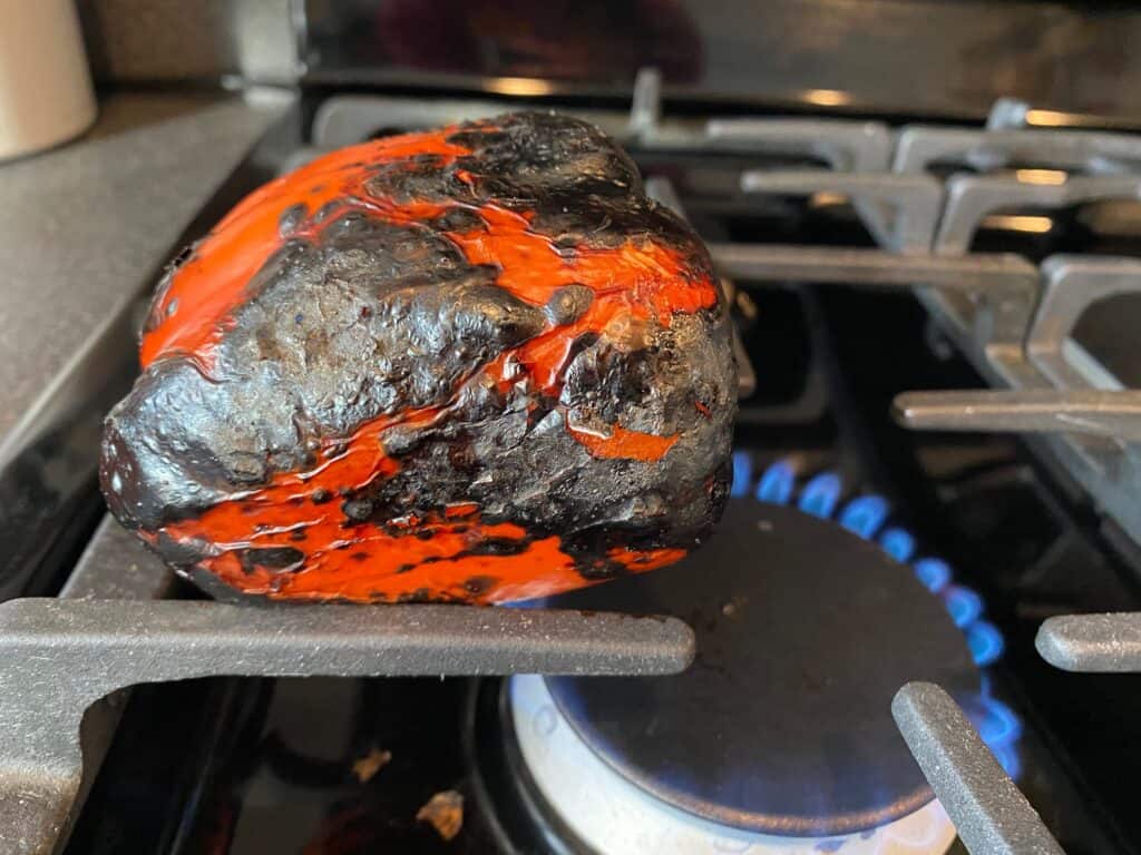 Charred red pepper over a flame.
