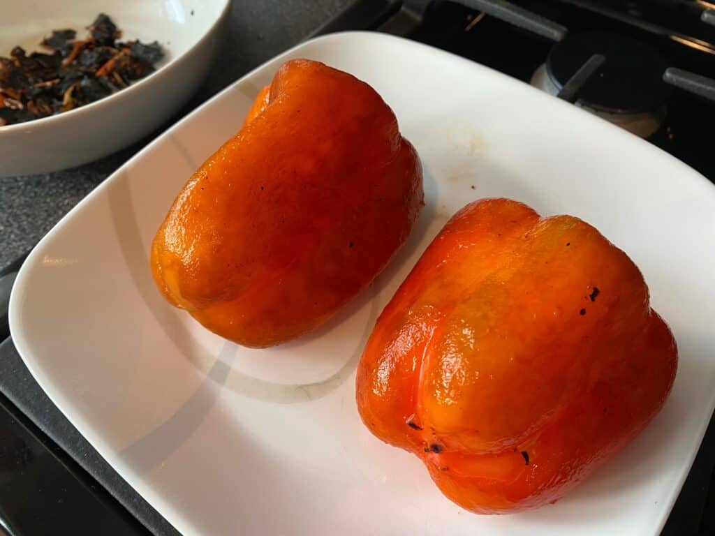 Peeled, roasted red bell peppers on a plate.