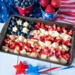 Small tray with strawberries, blueberries, and white peaches arranged in the shape of an American flag.