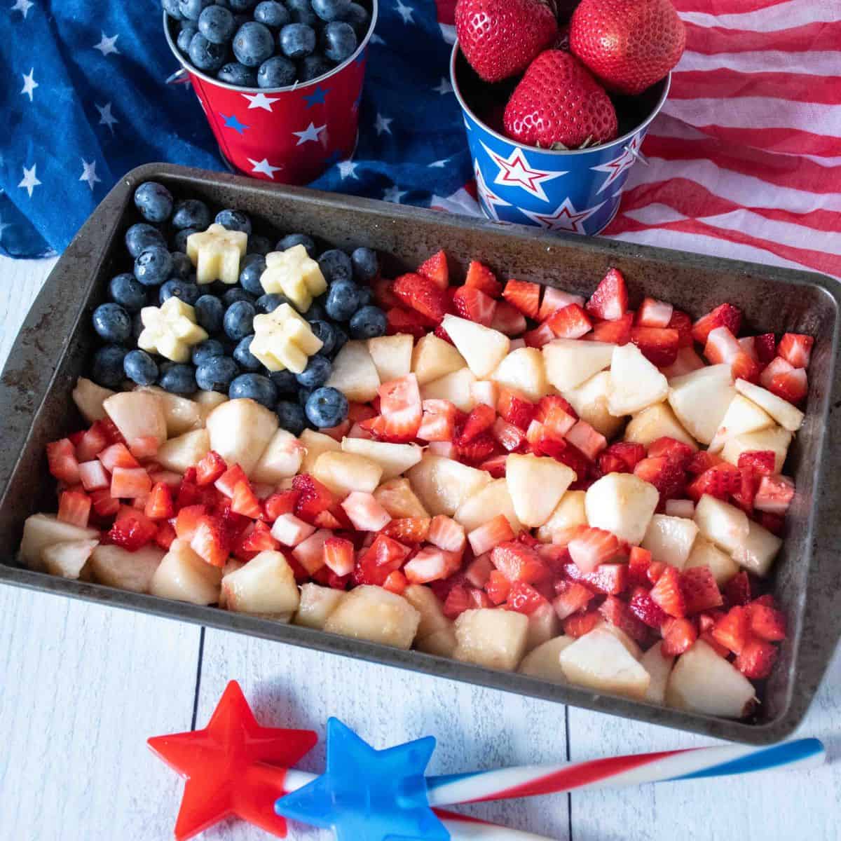 Small tray with strawberries, blueberries, and white peaches arranged in the shape of an American flag.