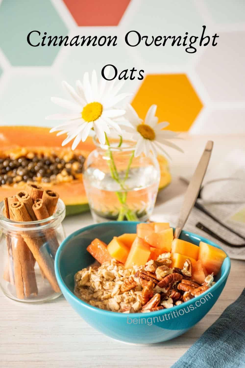 small bowl of oatmeal with chopped pecans and papaya. Text overlay: Cinnamon Overnight Oats.