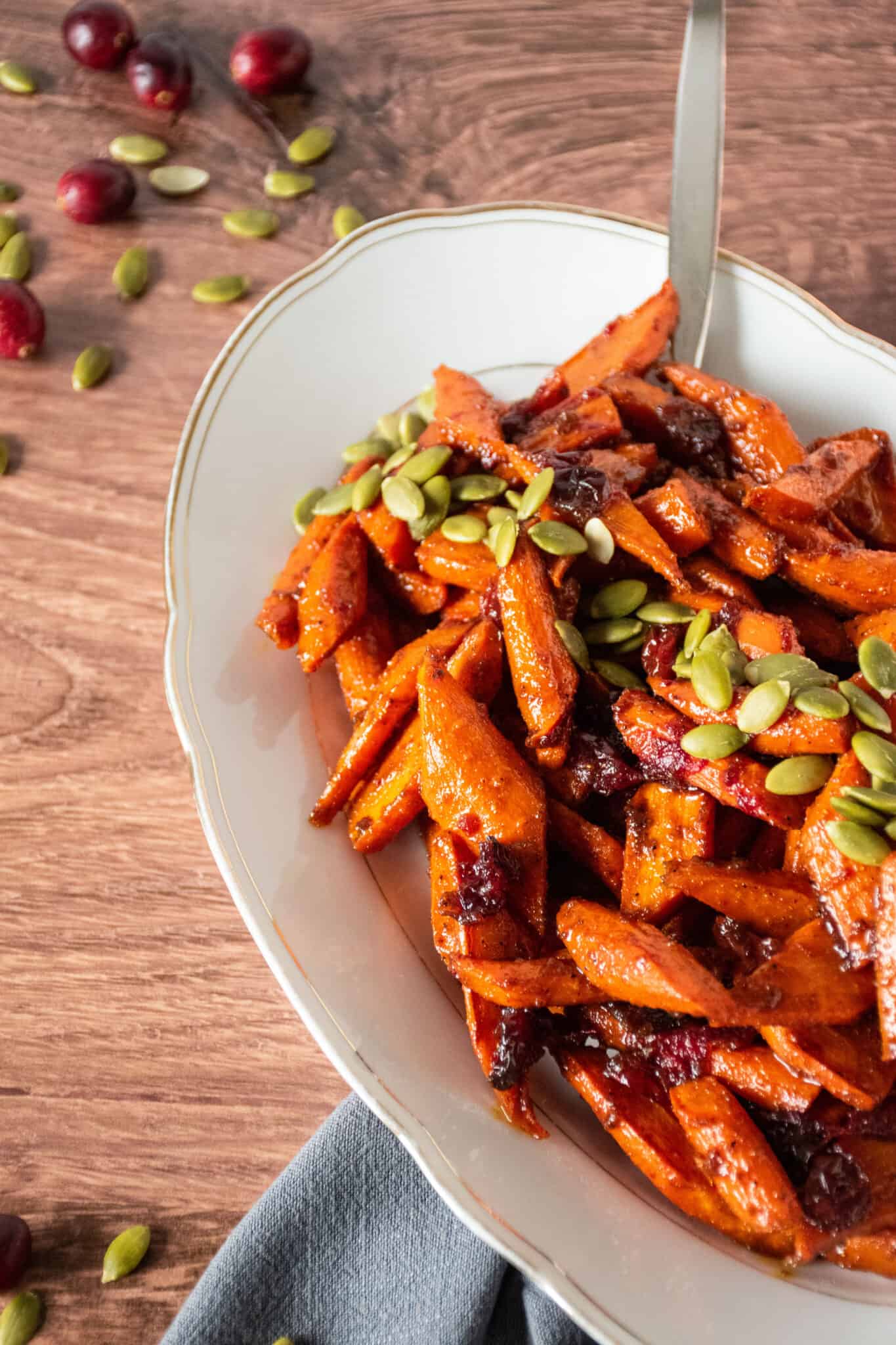 Oval plate with glazed carrots on it, garnished with pepitas.