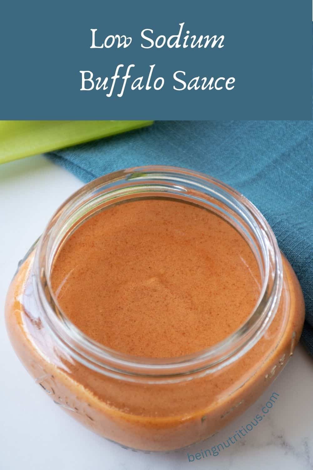 Buffalo sauce in a small jar, with celery sticks in the background. Text overlay: Low Sodium Buffalo Sauce.