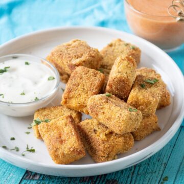 Crispy tempeh appetizers on a plate with ranch dressing in a small bowl.