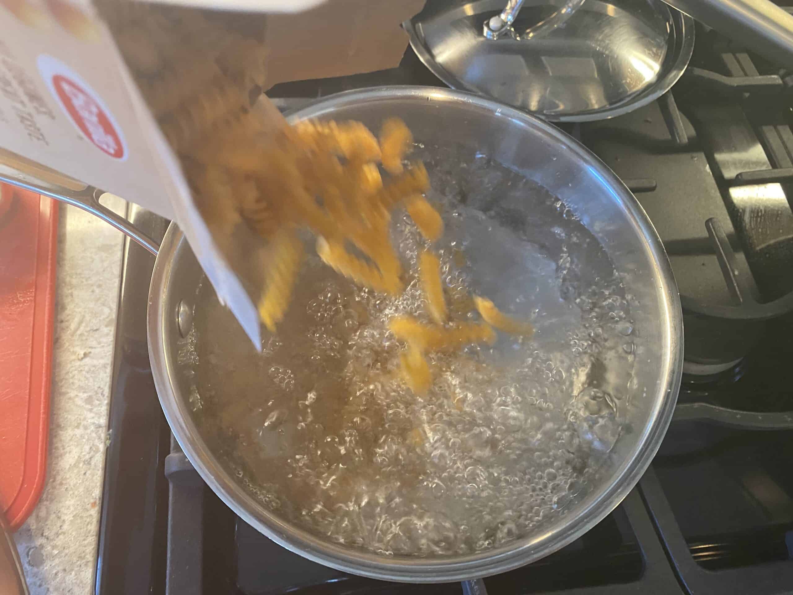 Pouring pasta into boiling water.