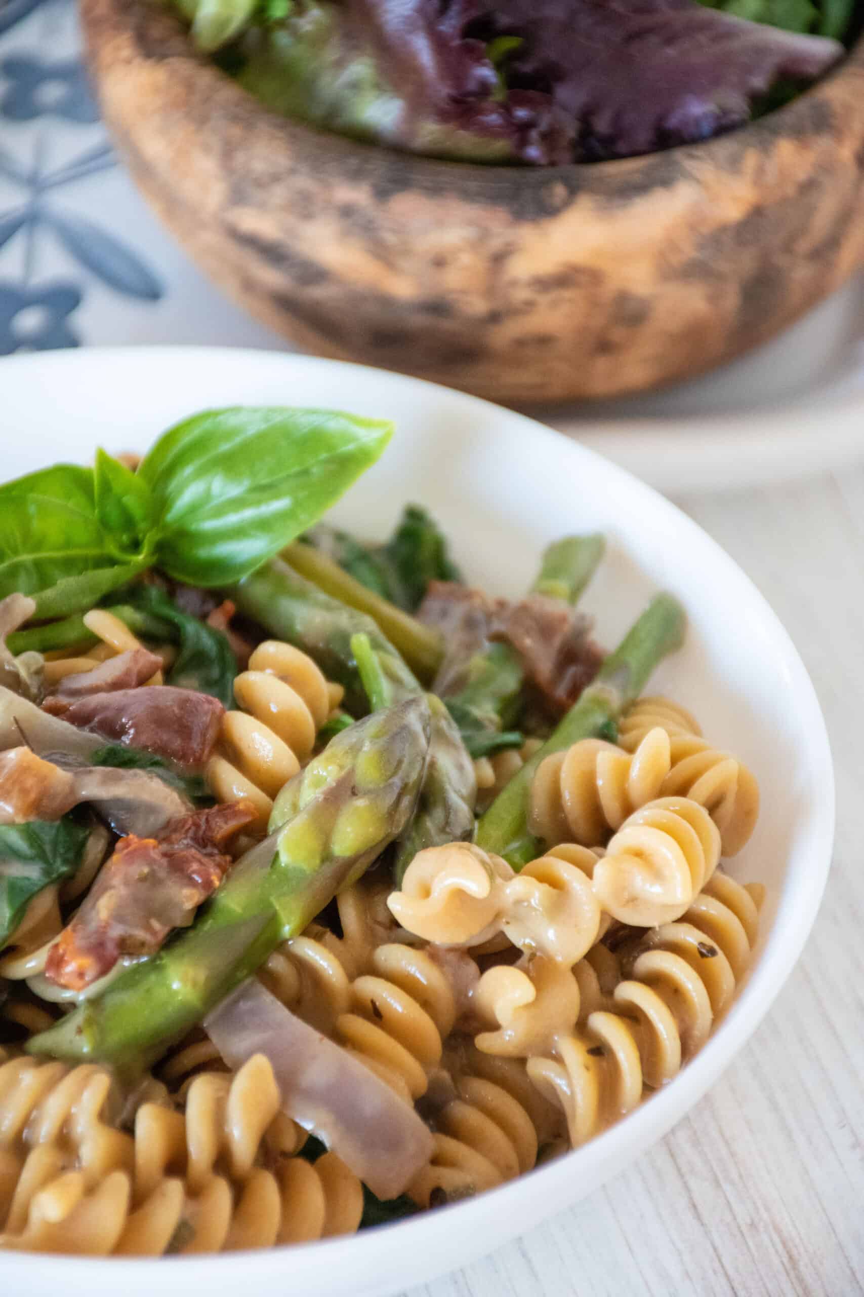 Close up bowl of creamy rotini pasta with vegetables.