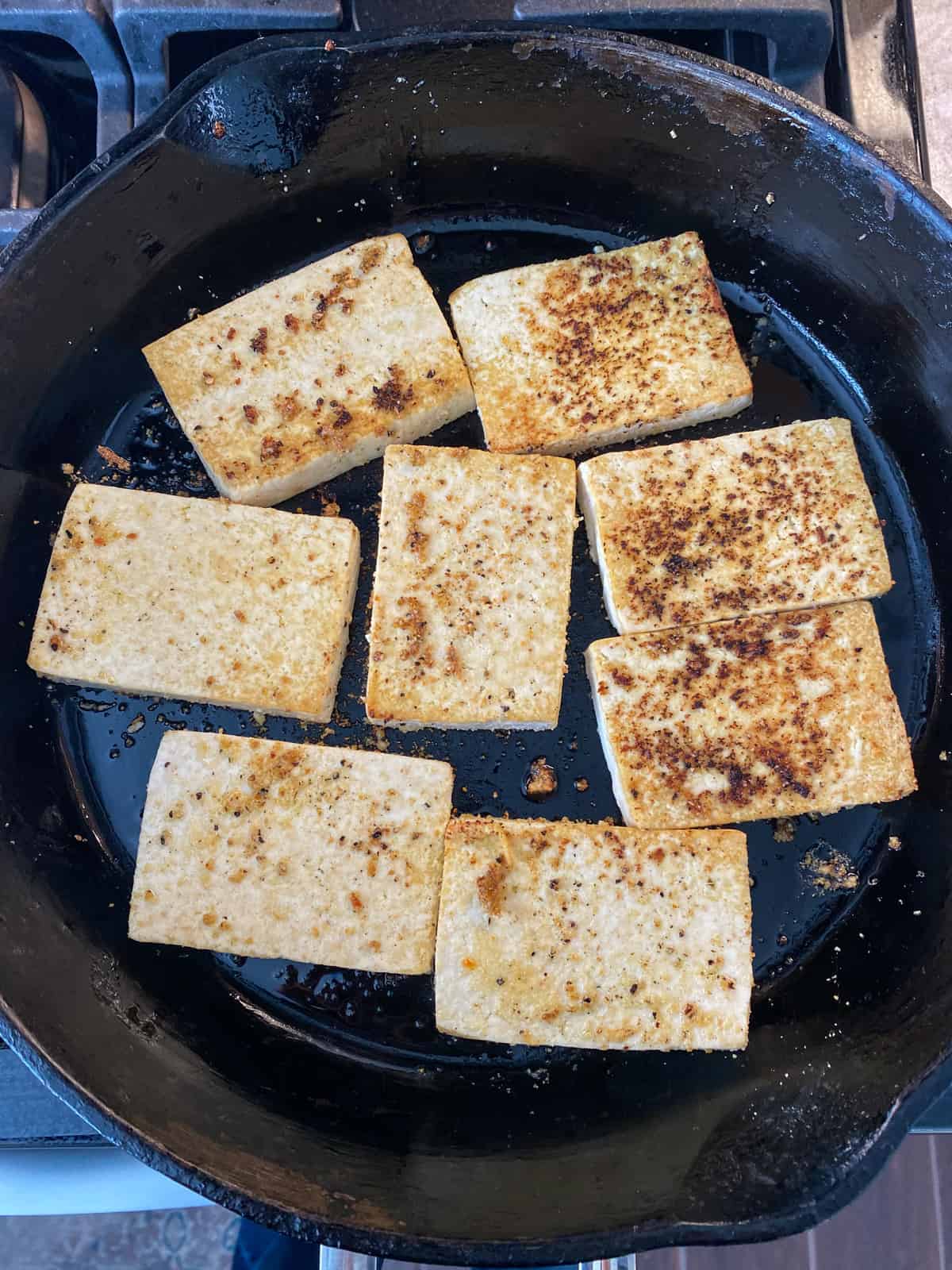 Skillet with tofu cooking in it.
