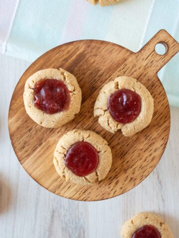 Overhead image of three thumbprint cookies on a platter with strawberry jam in them
