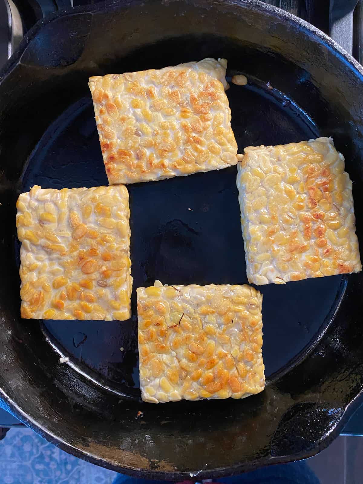 Cuts of tempeh, browned in a skillet.