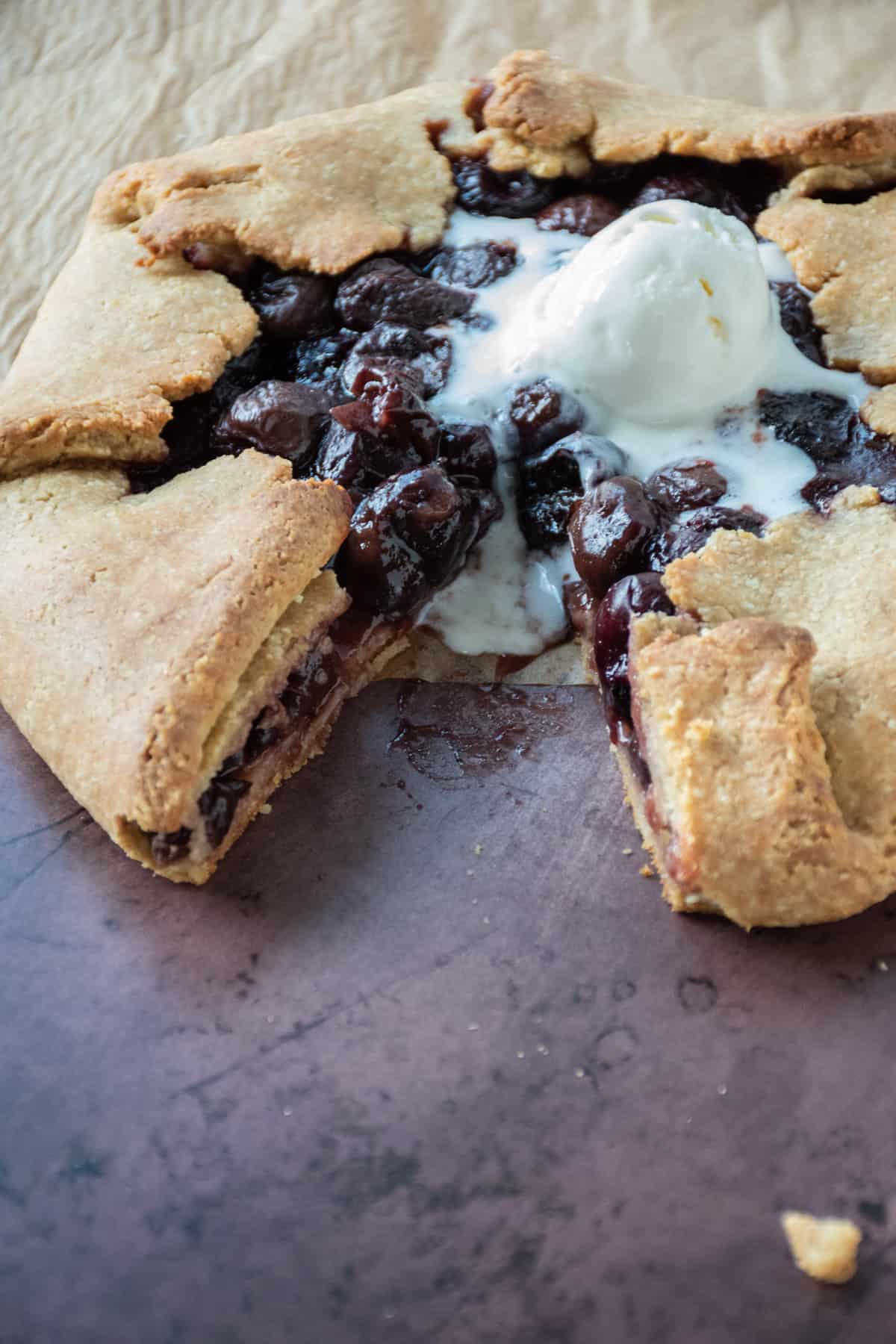 Cherry galette, with ice cream on top, and one slice removed.