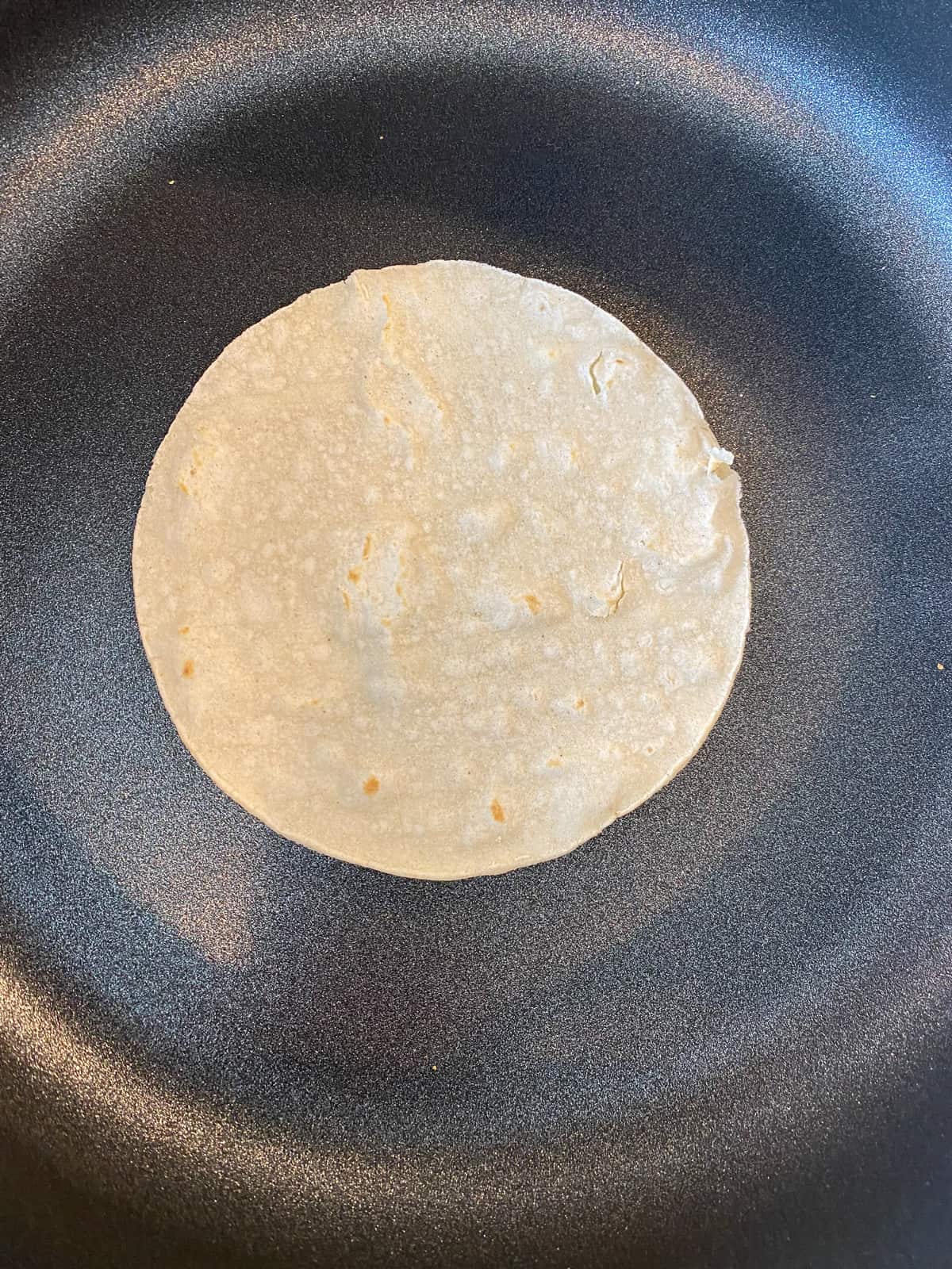 Corn tortilla flipped over in the skillet