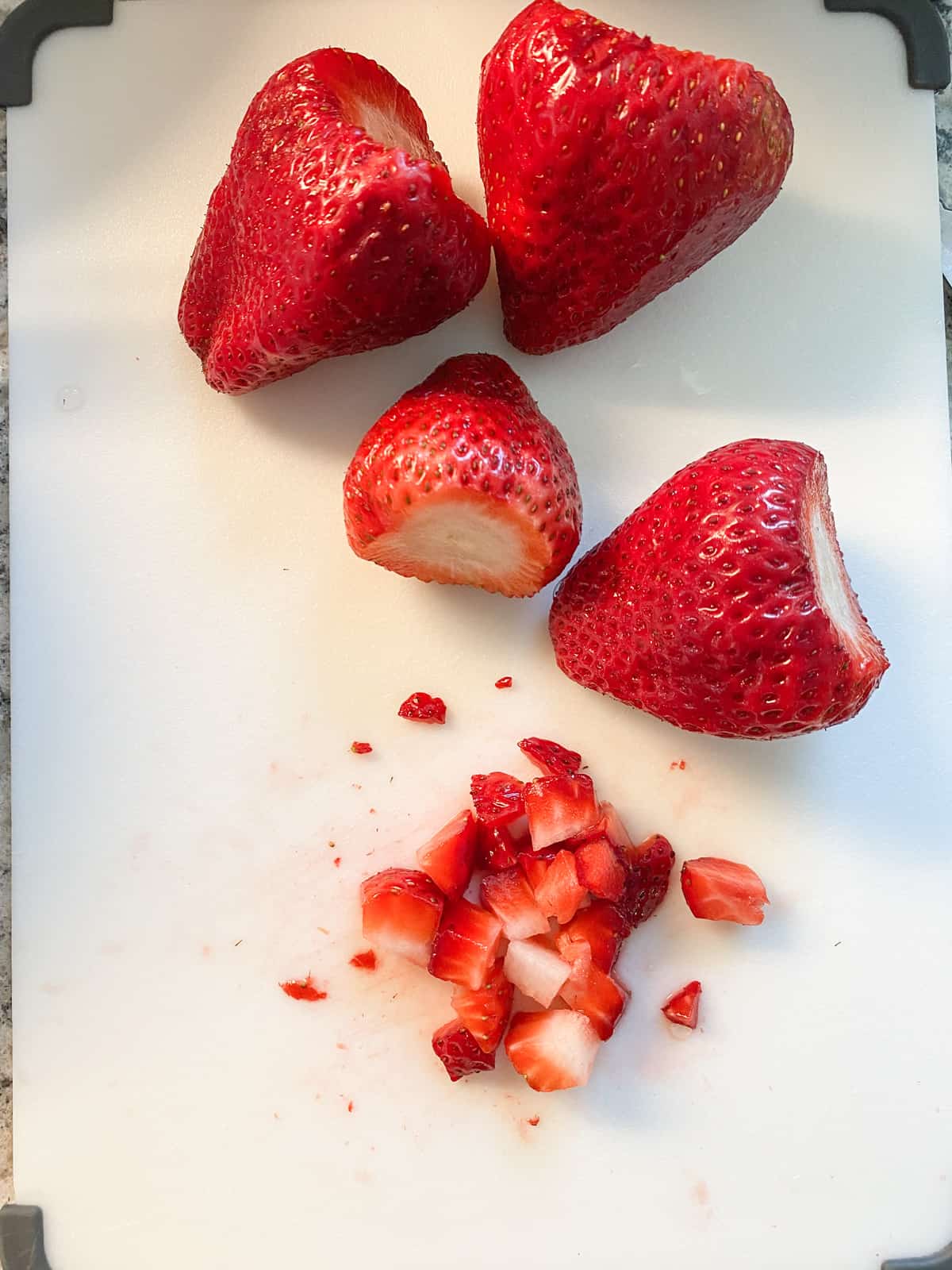 Diced strawberries on a cutting board.