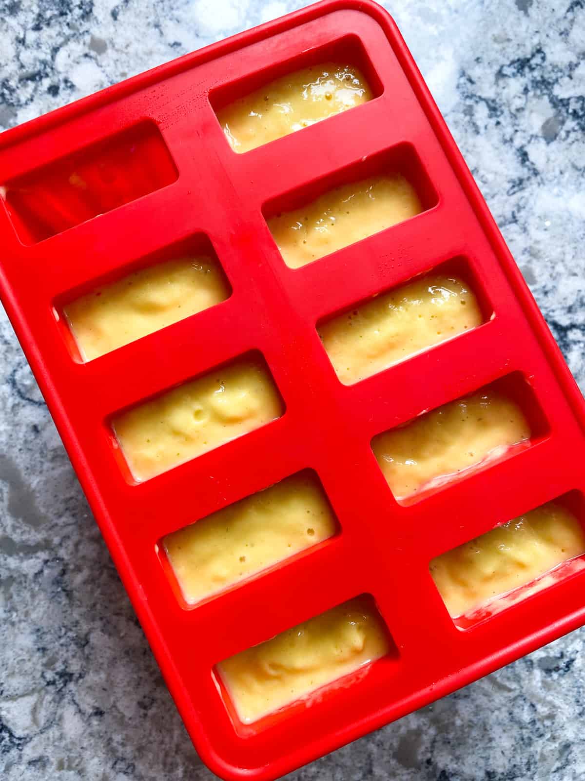 Popsicle puree poured into popsicle molds.
