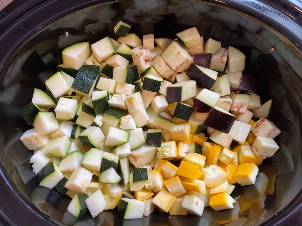 Chopped eggplant, zucchini, and yellow squash in the slow cooker.
