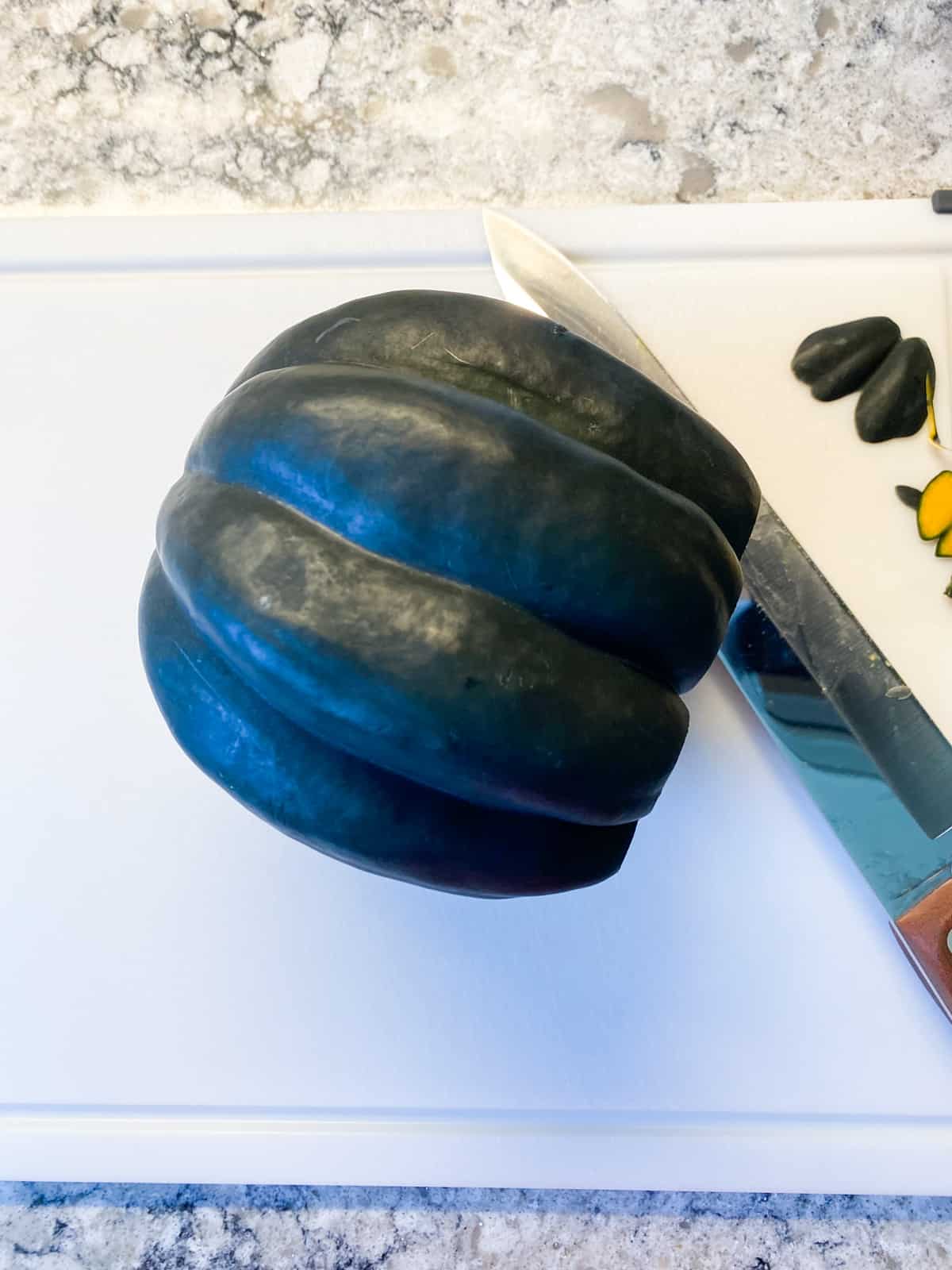 Whole acorn squash, with a small slice cut from the stem end, to create a flat surface for safe cutting.