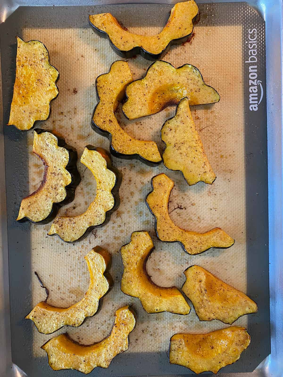 Sliced acorn squash, roasted, on a baking sheet.