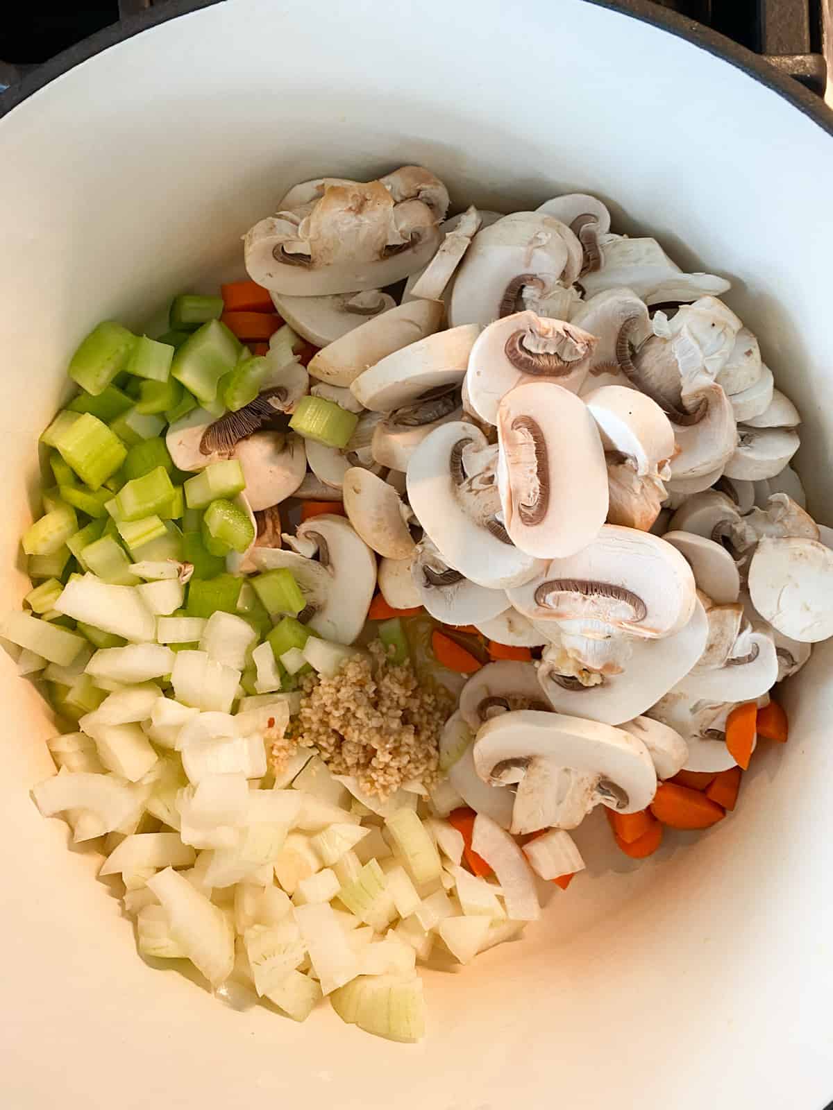 Chopped vegetables in a soup pot, sautéing.