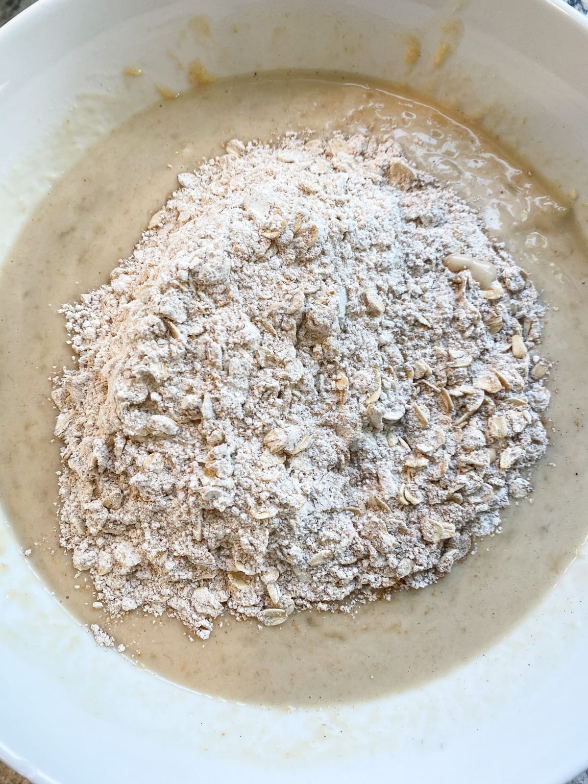 Dry ingredients added to wet ingredients, in a bowl.