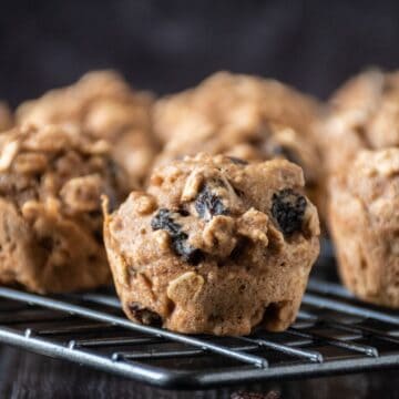 Close up of a mini muffin on a cooling rack with the rest of the muffins in the background.