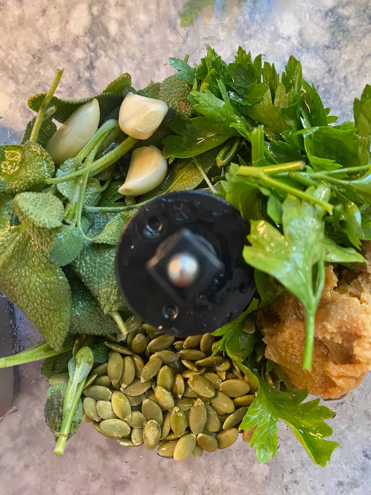 Whole ingredients for sage pesto in a food processor.