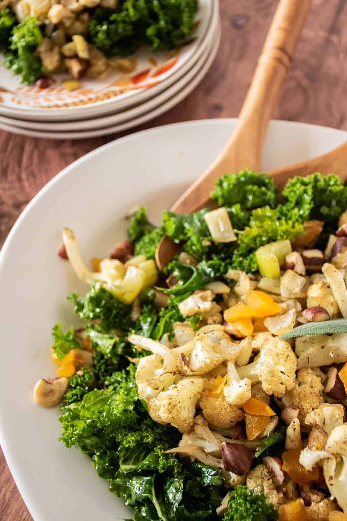 Large serving dish with kale and cauliflower on it, with serving utensils.
