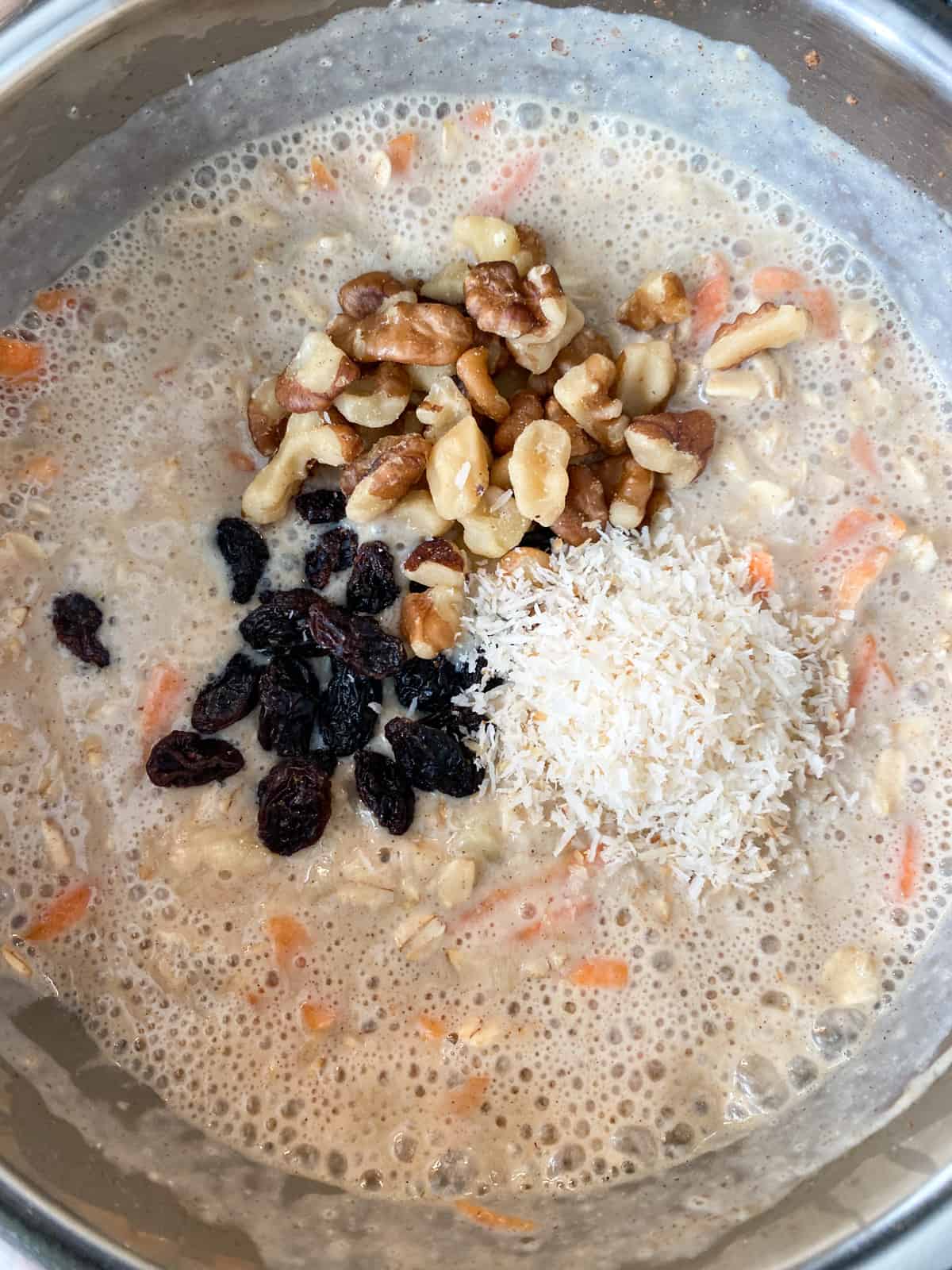 Oatmeal in a pot with raisins, coconut, and walnuts added.