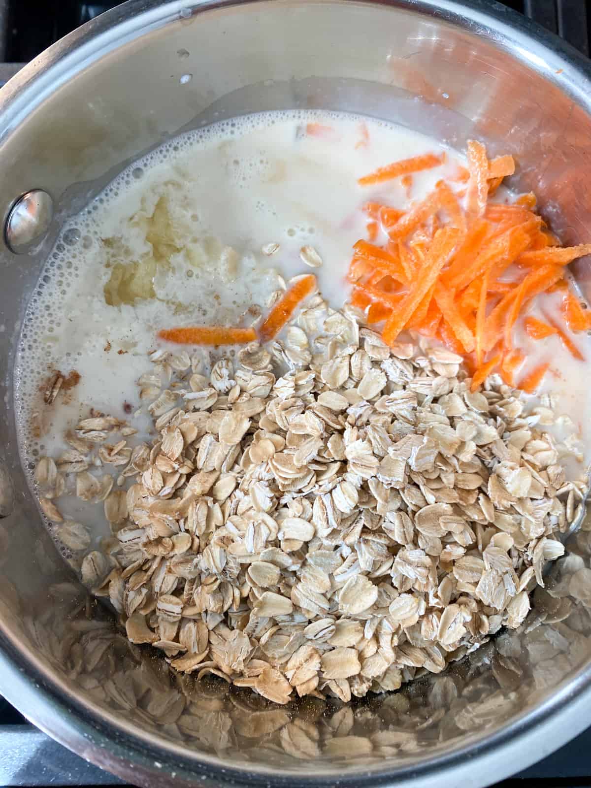 Raw ingredients for carrot oatmeal in a pot, ready to cook.