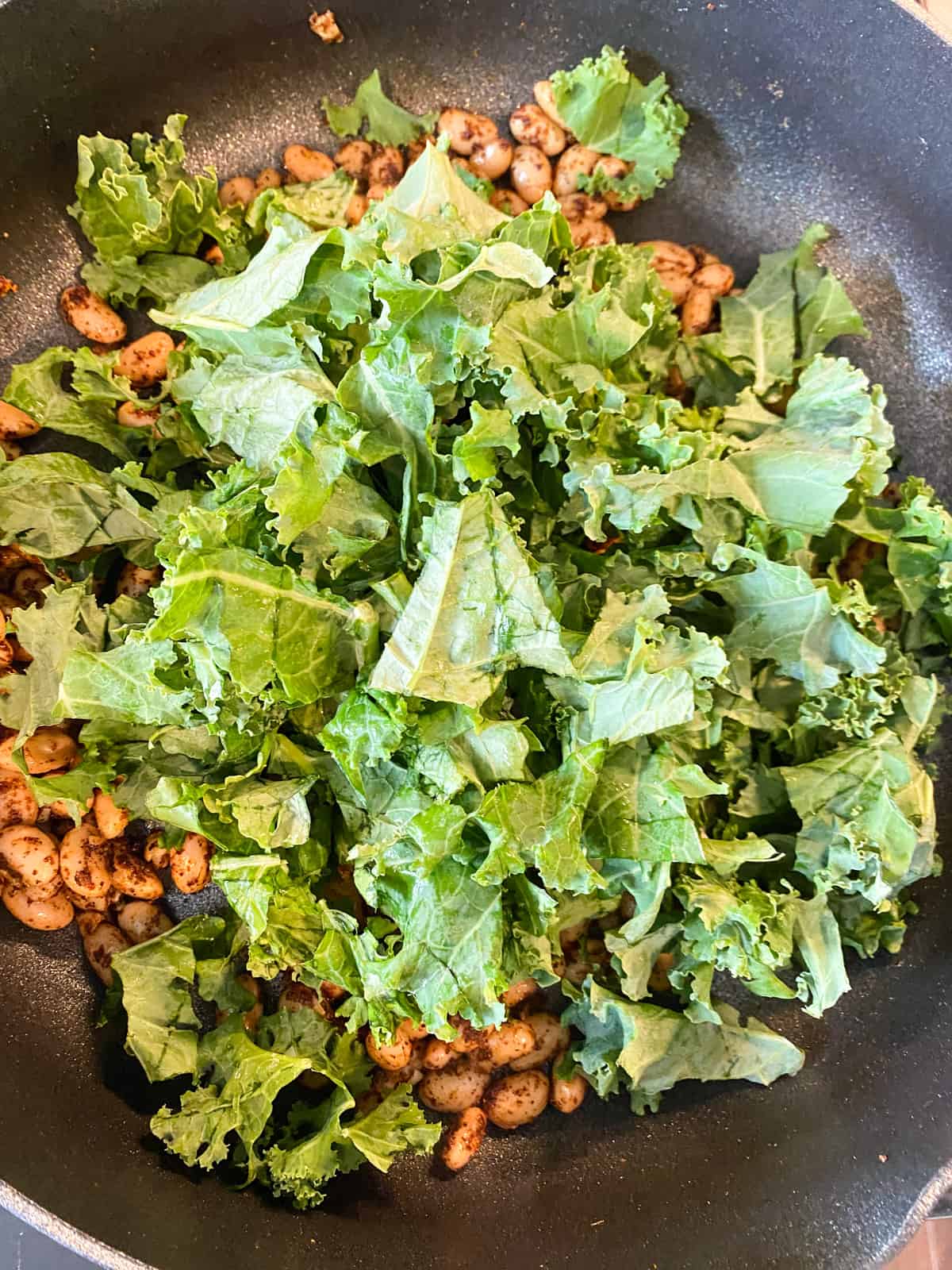 Chopped kale added to skillet.