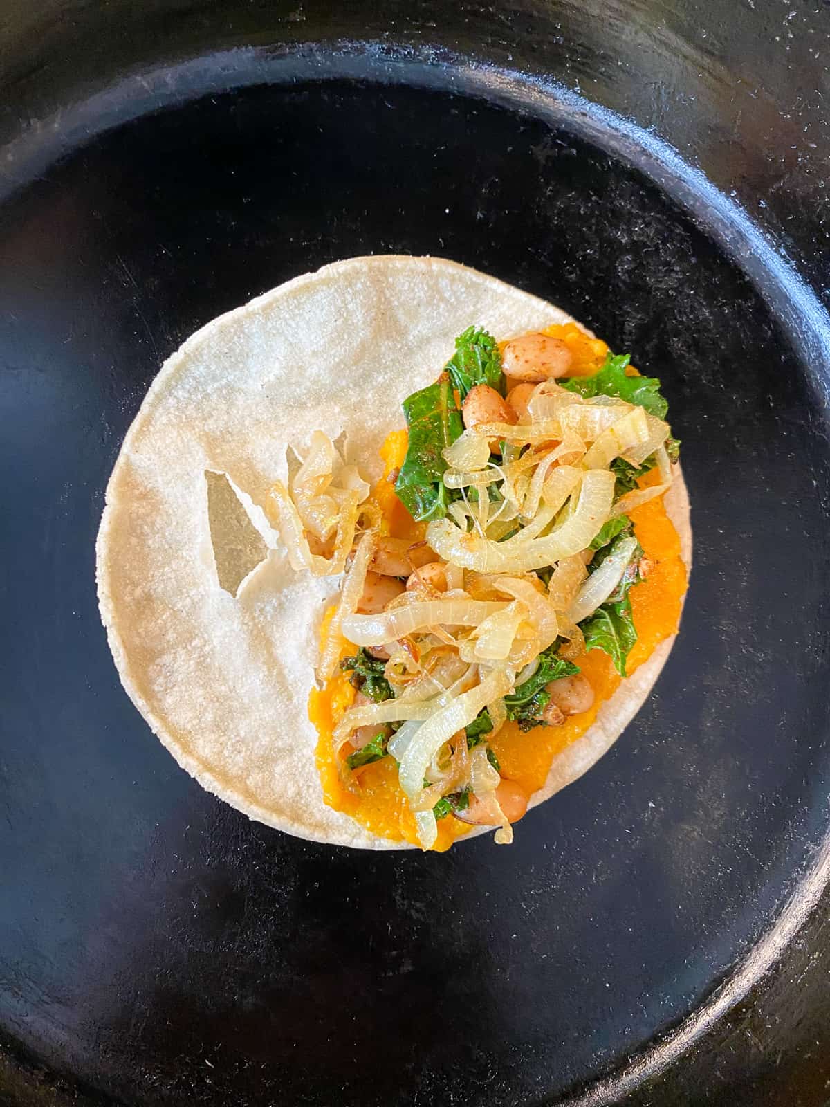 Tortilla with all the fillings piled on to one half, in a skillet.