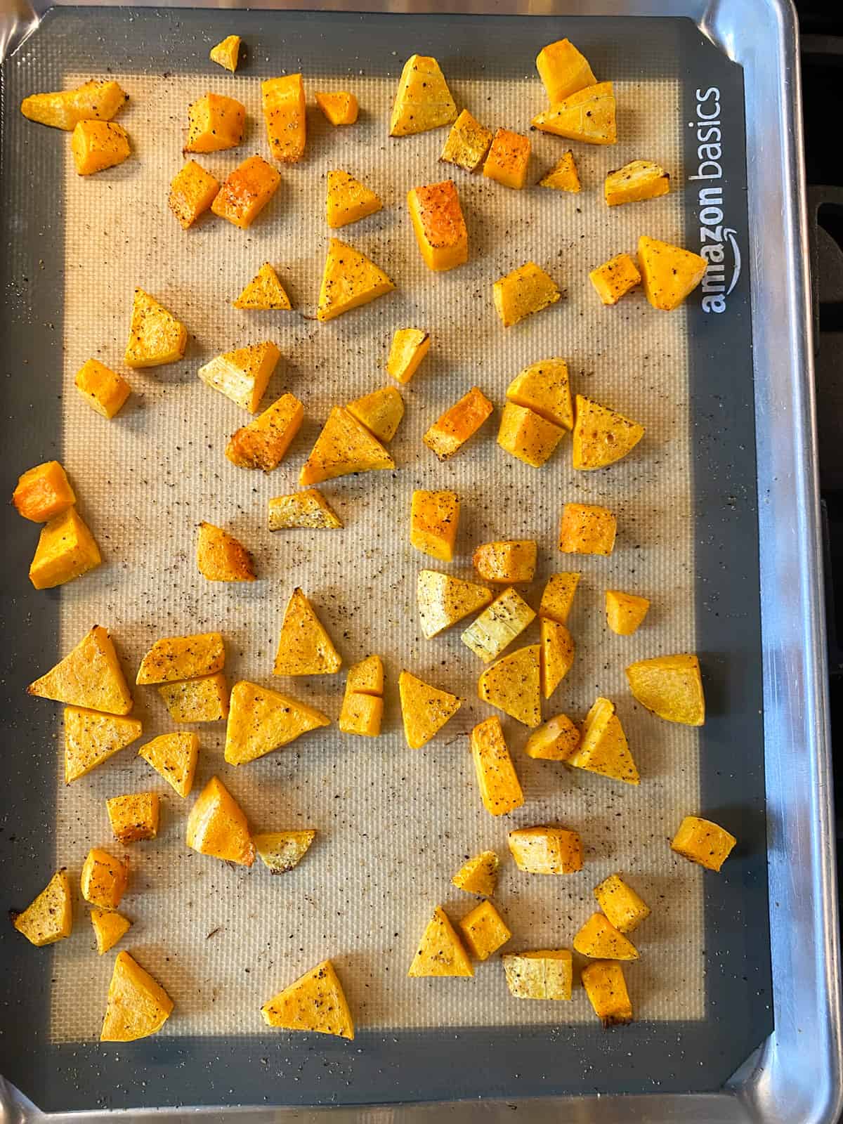Roasted butternut squash cubes on a baking sheet.