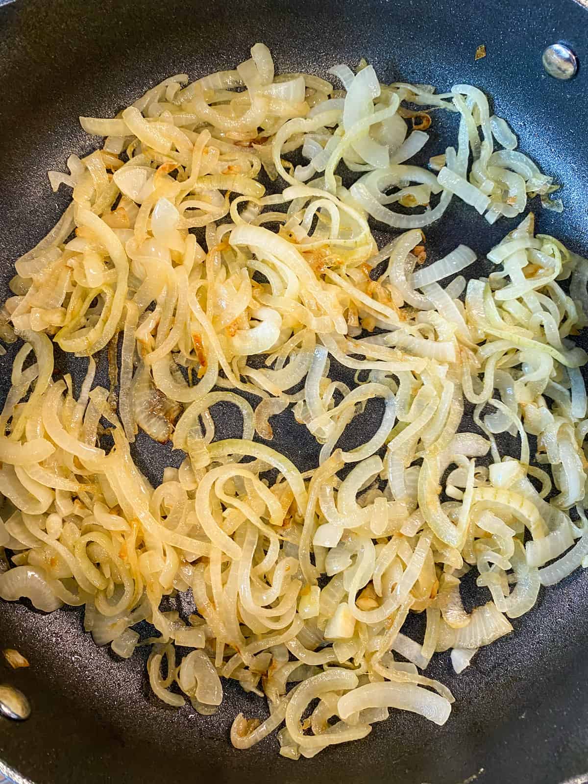 Onions sauteing in a skillet to make caramelized onions.
