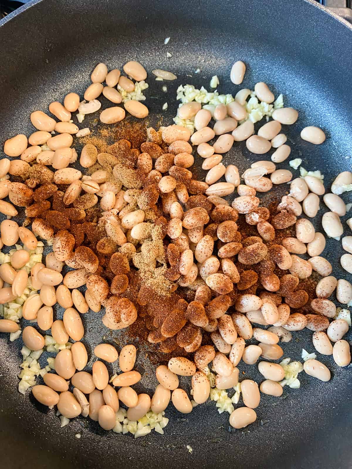 White beans with seasoning in a skillet.