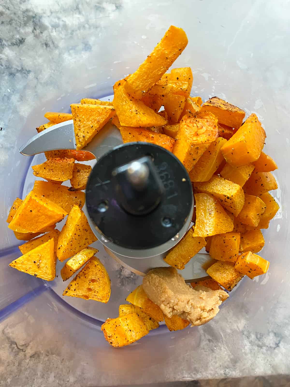Roasted butternut squash cubes in a food processor with miso paste.
