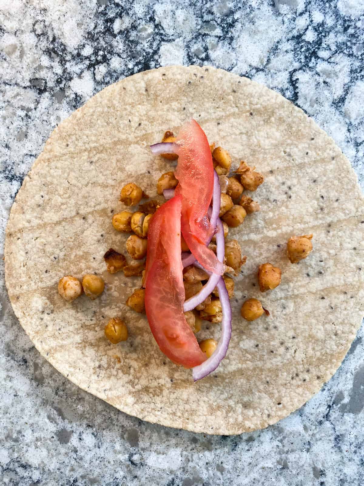 Wrap assembly: add the onions and tomatoes over the buffalo chickpeas.