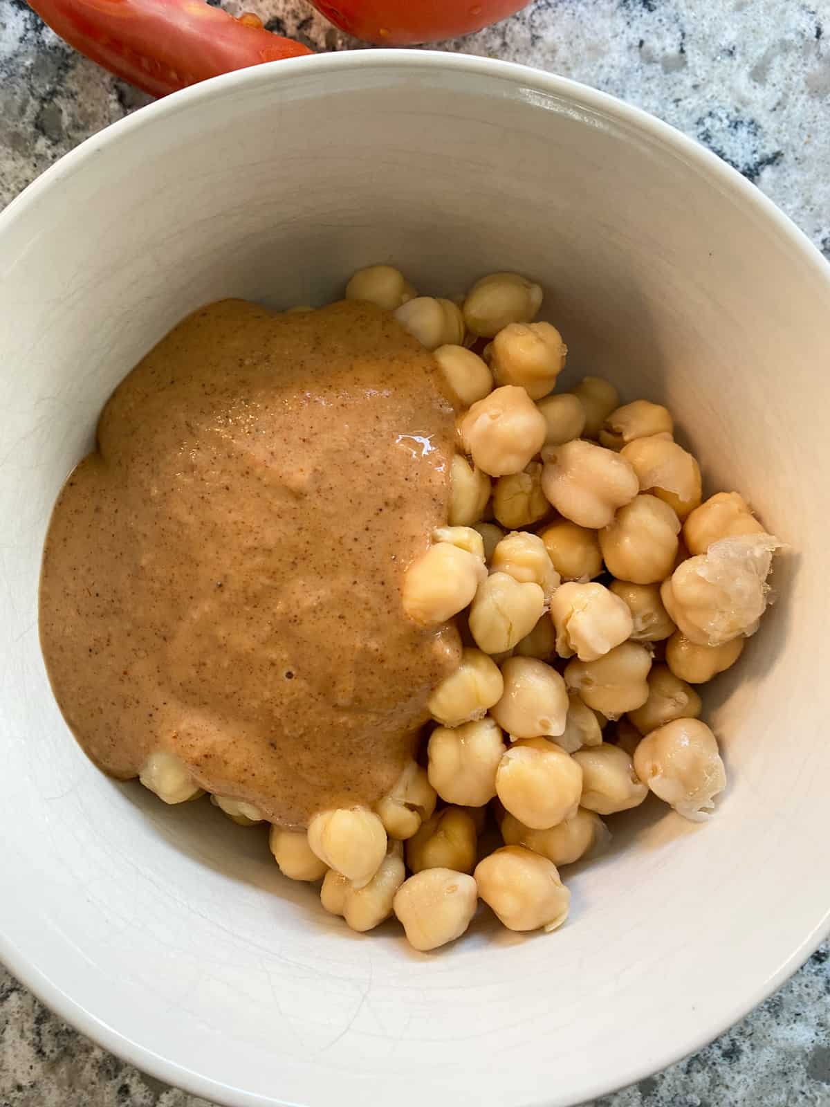 Chickpeas in a bowl with Buffalo sauce poured on top.
