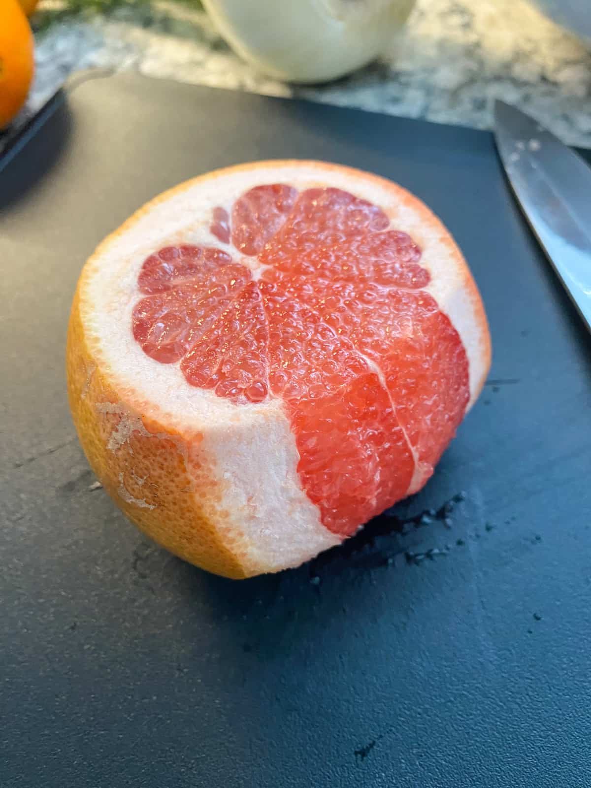 Grapefruit with both ends sliced off, and a few slices of peel and pith removed, demonstrating how to cut off the peel and pith.