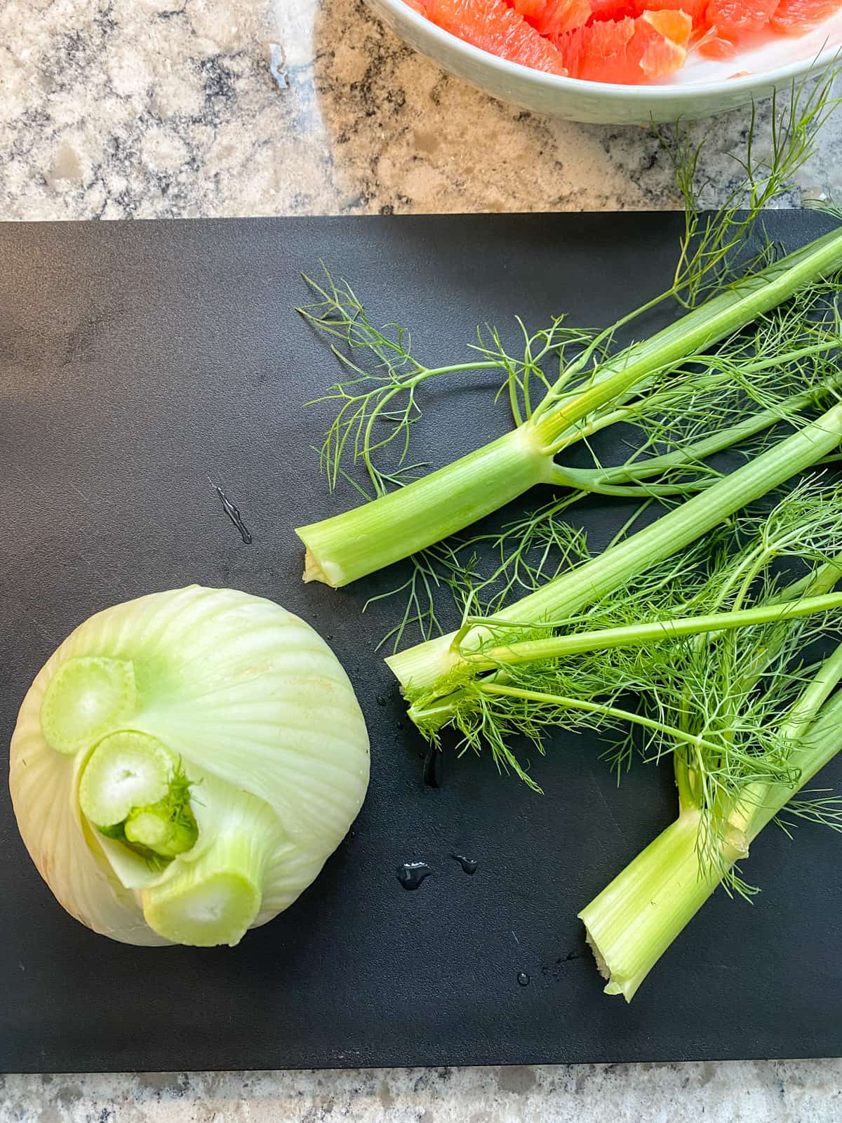 Fennel bulb on a cutting bowl, with top stems sliced off.
