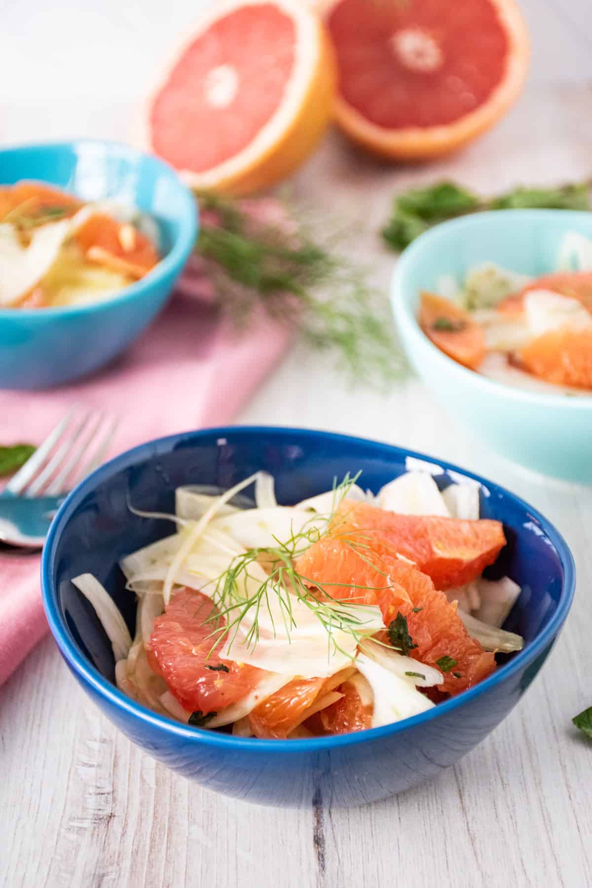 Salad with citrus and fennel in a small bowl, garnished with a fennel frond.