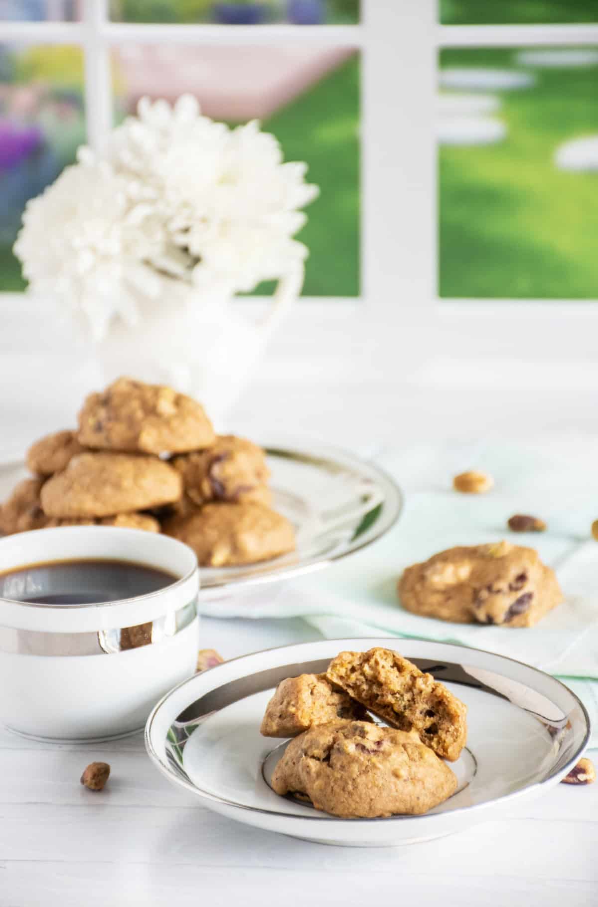 2 cookies on a small plate, one broken in half. A plate with a pile of cookies visible in the background.