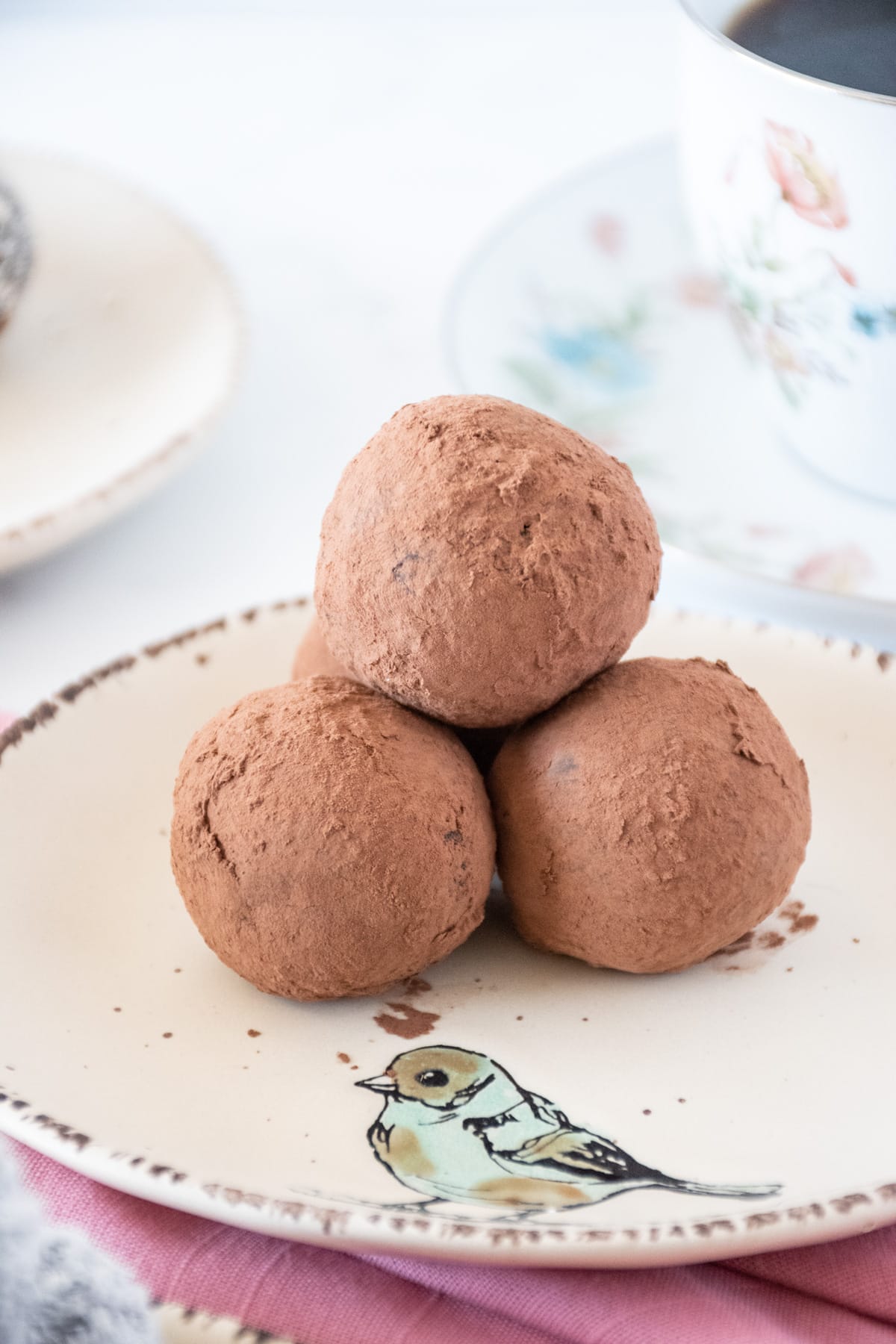 Homemade cherry truffles covered with cocoa powder, stacked on a small dish.