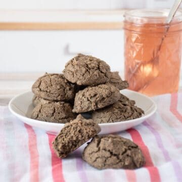 Plate of biscuits, with a jar of jam. Two additional biscuits off the plate, in the foreground.