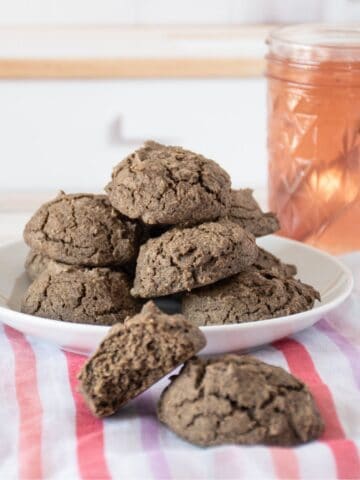 Plate of biscuits, with a jar of jam. Two additional biscuits off the plate, in the foreground.
