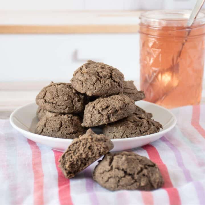 Plate of biscuits, with a jar of jam. Two additional biscuits off the plate, in the foreground.
