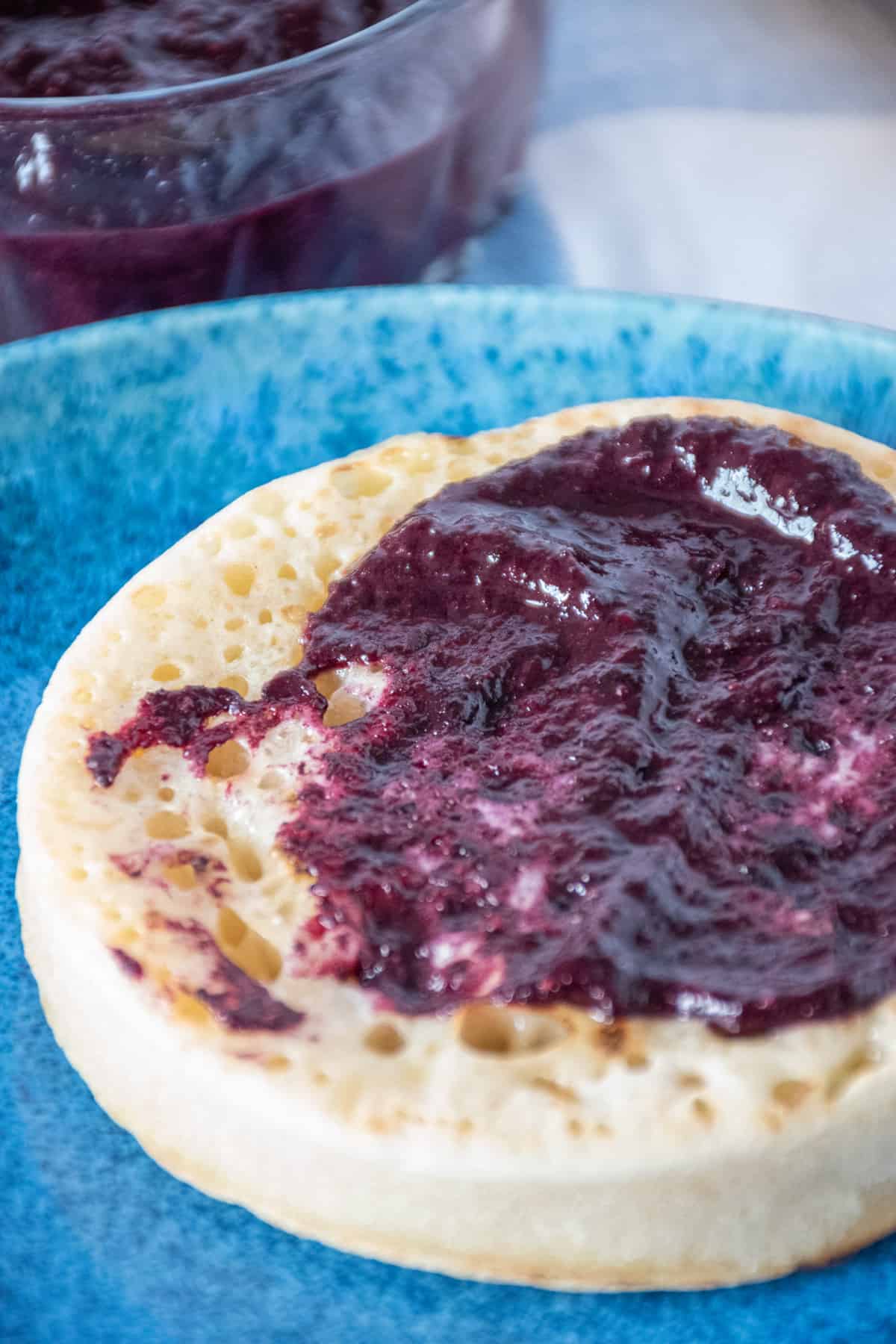 Close up of blueberry chia jam smeared on a toasted crumpet.
